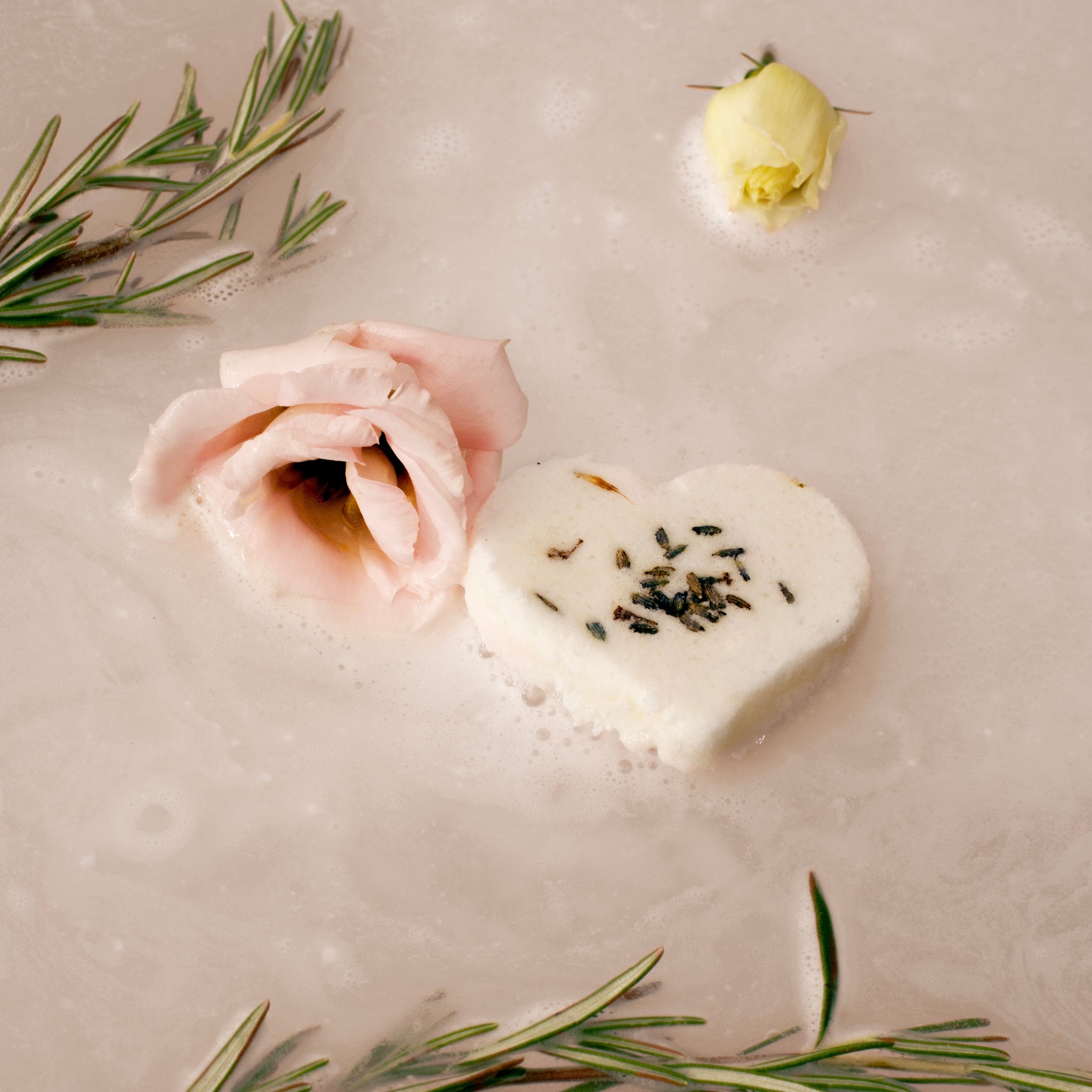 Heart-shaped shower steamer with rose petals and rosemary in water