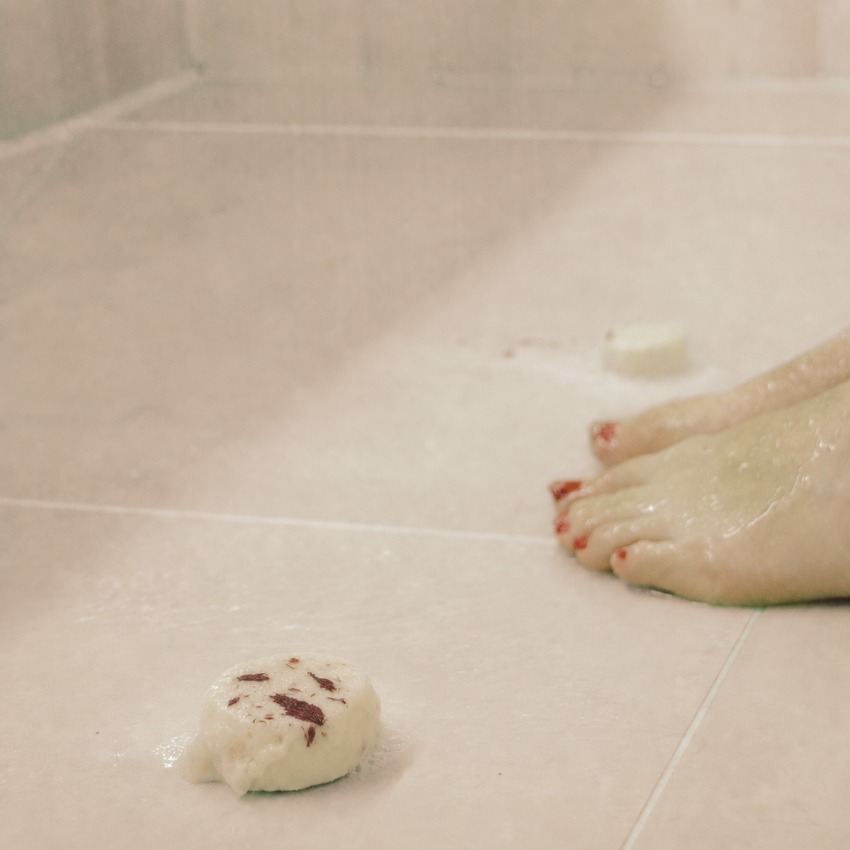 Red Ember Atelier shower steamer in use on wet shower tiles.