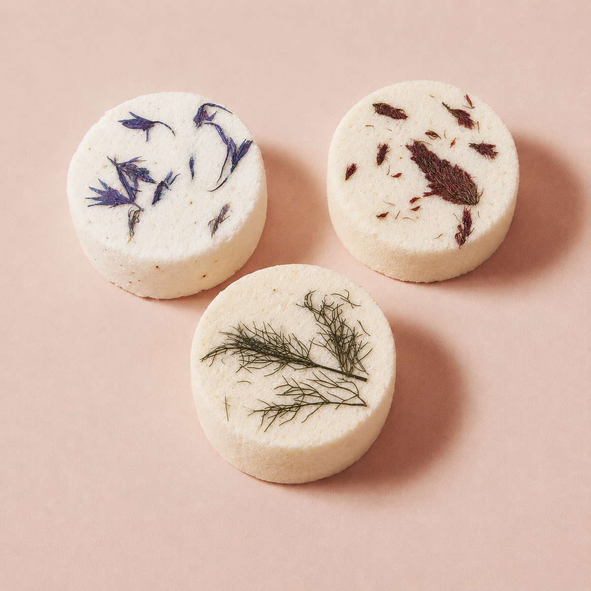 Atelier Shower Steamer Trio with Blue Marine, Red Ember and Emerald Garden on a soft blush background.