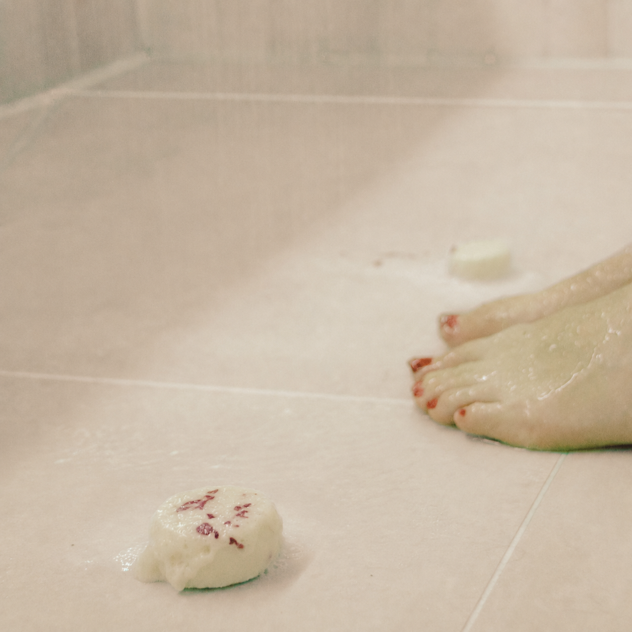Serenity rose petal aromatherapy shower steamer melting on wet shower tiles during a spa-like shower ritual.
