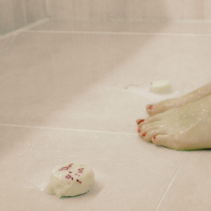 Serenity rose petal aromatherapy shower steamer melting on wet shower tiles during a spa-like shower ritual.