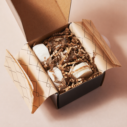 Open Sunday Steam gift box with aromatherapy shower steamers wrapped in patterned tissue paper and eco-friendly paper filling.