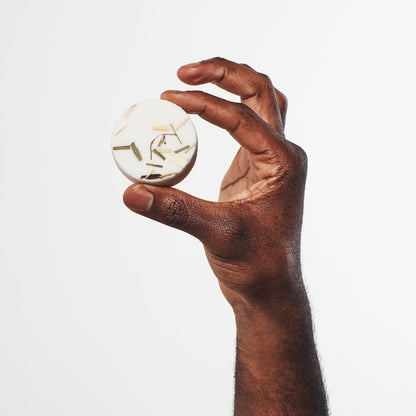 Sunday Steam Clarity shower steamer with lemongrass and bergamot held in hand against a clean white background.