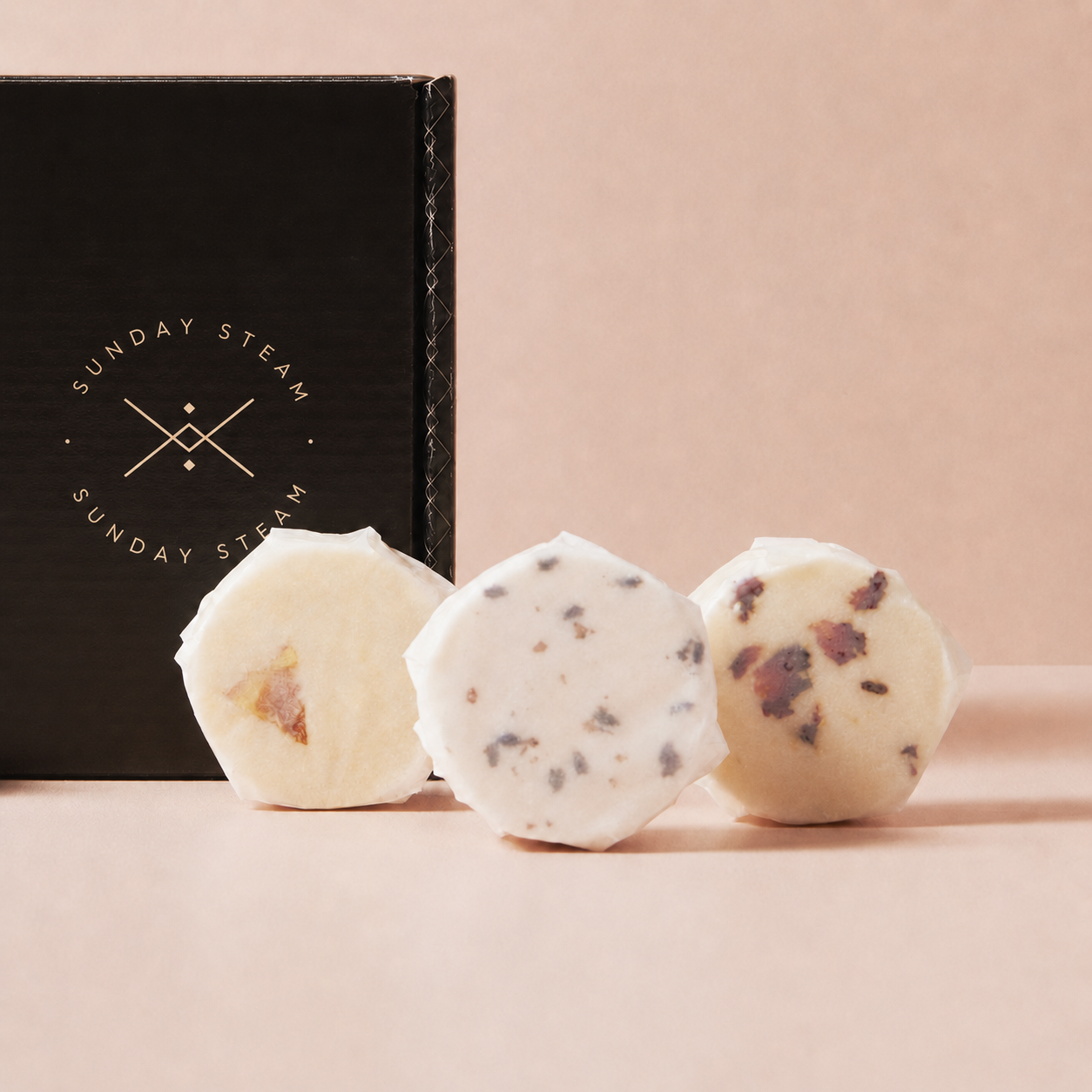 Sunday Steam Mindful Moments shower steamers displayed in front of a black gift box on a soft pink background.